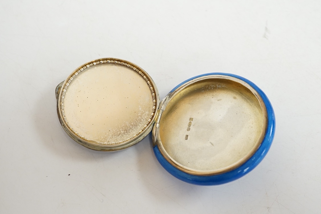 A George V silver and enamelled circular compact, the cover depicting a lady and gentleman, import marked for P.H. Vogel & Co, London, 1924, diameter 51mm.